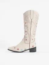Botas tejanas de cuero vegano color crema con bordados de estrellas rojas y azules.