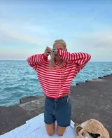 Saquito de lana peinada a rayas horizontales rojas y blancas, con cuello redondo y cierre frontal con botones.