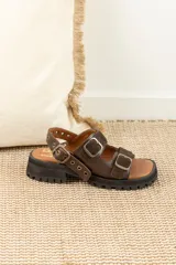 Sandalias de cuero marrón con plataforma track y hebillas metálicas.