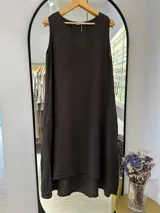 Vestido midi sin mangas color chocolate, confeccionado en lino puro, con escote redondo y bolsillos laterales. Tiene corte acampanado y costuras que le aportan estructura.