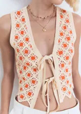 Top de crochet color crudo con flores naranjas, sin mangas, con escote en V y cierre frontal con lazos.