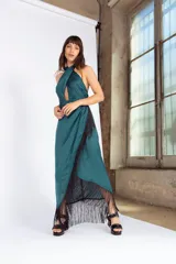 Vestido largo de seda lavada color verde esmeralda, con escote cruzado, falda en capas y flecos negros en el ruedo.
