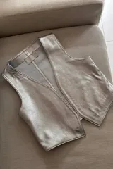 Chaleco plateado de cuero ovino, con cuello en V y sin cierre.