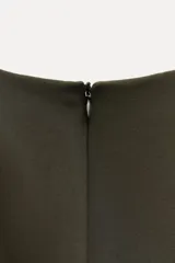 Vestido midi de cuello redondo y manga larga con puños. Tiene detalle de drapeado lateral y cierre trasero con cremallera oculta en la costura.