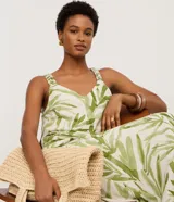 Musculosa femenina confeccionada en una mezcla de viscosa y lino, con estampado de follaje verde sobre fondo crudo. Presenta un cuello en V y breteles anchos con detalle fruncido, ofreciendo un calce regular y fluido.