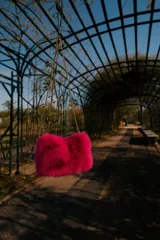 Cartera de mano color fucsia, con textura de piel sintética y cadena dorada.