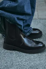 Botín Chelsea de cuero negro con elásticos laterales, tirador trasero y suela track con plataforma.