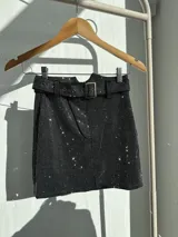 Minifalda negra cubierta de strass plateado con cinto incluido y cierre metálico al frente.