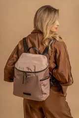 Mochila urbana de diseño compacto, color violeta/malva, con acabado ligeramente brillante. Presenta un compartimento principal con doble cierre superior y bolsillos laterales con cierre.