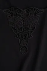 Top corto negro de punto suave con escote cuadrado amplio y bajo recto. Modelo de manga corta con ajuste entallado y detalle en V en broderie en el centro del busto.