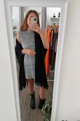 Ruana tejida color negro con diseño calado y flecos en los bordes.