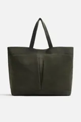 Bolso tipo shopper color verde musgo, confeccionado en cuero con acabado serraje. Tiene compartimento principal con cierre magnético, cuatro bolsillos exteriores y un bolsillo interior con cierre.