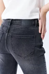 Pantalón de jean negro con corte cropped y flare, de tiro alto y con terminación desflecada.