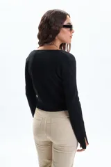 Saco de tejido punto negro con hilo de Lurex, escote en V y cierre frontal con botones. Presenta aberturas en los puños de las mangas largas.