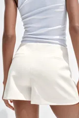 Falda pantalón corta color blanco, de tiro medio con abertura en el delantero y cierre lateral con cremallera.