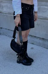 Bolso bandolera negro de cuero sintético con tachas plateadas en las correas.