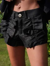 Short negro de lino con cintura alta, botón blanco y volados frontales.