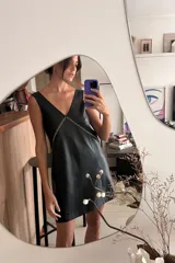 Vestido corto negro de cuero ovino, corte holgado, escote en V y bordado a mano en el frente.