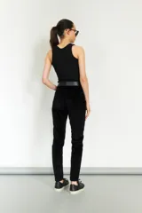 Pantalón de pana negro, corte slim, con cintura alta y cierre frontal con botón y cremallera.