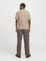 Polo de punto color beige con cuello clásico, mangas cortas y cierre con botones.