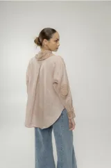 Camisa blanca de lino con cuello clásico, cierre frontal con botones y manga larga. Presenta detalles de crochet en cuello, puños y bolsillo.