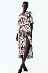 Vestido midi camisero color marrón con estampado floral blanco, cuello camisero, botonadura frontal y mangas cortas. Incluye cinturón extraíble para atar.