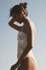 Traje de baño enterizo con estampado de hojas en tonos amarillo y blanco, breteles finos y escote recto.