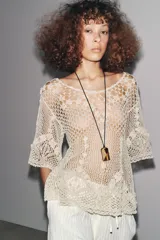 Top de crochet color crema, con cuello redondo y mangas cortas.