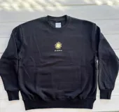 Buzo negro de corte oversize con cuello redondo y puños acanalados. Estampado en la espalda con dos palmeras y un sol en tonos verde y amarillo.