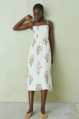 Vestido midi blanco con estampado floral multicolor, escote cuadrado y breteles finos ajustables.