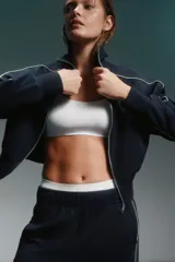 Conjunto deportivo azul marino con detalles de ribete blanco. Incluye una campera corta con cierre y un pantalón de corte recto.
