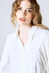 Camisa blanca de mangas largas abullonadas, con cuello mao y cierre frontal con botones.