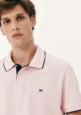 Chomba color beige con cuello polo y mangas cortas con ribete azul marino. Tiene un pequeño logo bordado en el pecho.