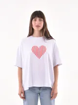 Remera blanca de corte holgado con estampa de corazón rojo con rayas verticales.
