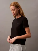 Remera negra de algodón con cuello redondo y mangas cortas. Presenta un logo bordado en el pecho.