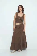 Falda larga maxi de algodón color marrón, con textura acanalada sutil. Presenta cintura elástica con cordón de ajuste y estructura en paños que añaden volumen y caída fluida.