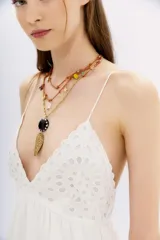 Vestido corto negro con breteles finos, escote en V, espalda baja con elástico, volados en el ruedo y bordados cut-out en el frente.