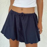 Pollera corta azul marino con finas rayas blancas verticales, cintura elastizada con cordón ajustable y ruedo con terminación festoneada.