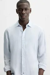 Camisa celeste de lino, de corte recto, manga larga y cuello clásico.