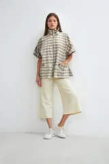 Capa acampanada color beige con manga corta, cierre metálico a la vista, cuello recto, bolsillos con tapa y terminaciones envivadas. Confeccionada en lana fina sin teñir, diseñada exclusivamente por Don Baez.