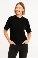 Remera negra de poliéster, manga corta, corte holgado y cuello redondo.