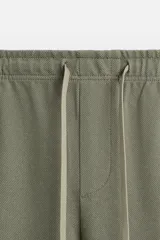 Pantalón de jogging color beige confeccionado en tejido de mezcla de algodón. Cuenta con cintura elástica ajustable con cordón, bolsillos frontales y traseros.