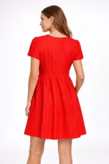 Vestido corto negro de broderie, con mangas cortas abullonadas y escote en V. Presenta un corte imperio con frunce en la cintura y falda acampanada.