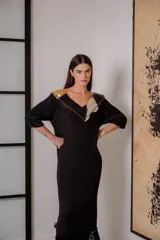 Vestido negro de noche con mangas 3/4, cuello en V con detalles de cuero entrelazado, terminación en flecos y tajos laterales.