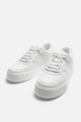 Zapatillas deportivas blancas de estilo retro con suela de plataforma.