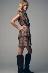 Vestido corto con estampado de cachemira en tonos marrones, beige y verde. Tiene escote en pico con abalorios, mangas cortas y cintura elástica con cinturón fino.