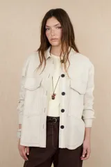 Sobrecamisa color crema con botones negros, cuello camisero, dos bolsillos de parche en el pecho y costuras a contraste.