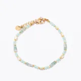 Pulsera de cuentas doradas, con cuentas facetadas de color celeste claro, cuentas planas de nácar o piedra blanca y cuentas rectangulares de piedra verde agua. Cuenta con un cierre de mosquetón y cadena de ajuste dorada.