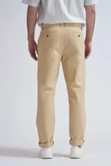 Pantalón chino color beige de corte recto con bolsillos laterales y traseros. Tobillos con dobladillo.