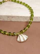 Collar corto de cuentas facetadas color verde oliva y dije de caracola blanca con detalles dorados.